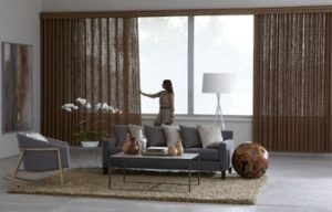 Wide view of a living room where a woman is opening the curtains in front of a large window
