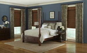 A master bedroom with brown shades and light green curtains on the windows