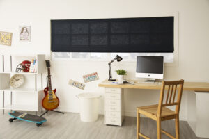 Picture of a home office with black shades installed on the window.