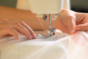 The process of sewing curtains from a mesh of white fabric. 